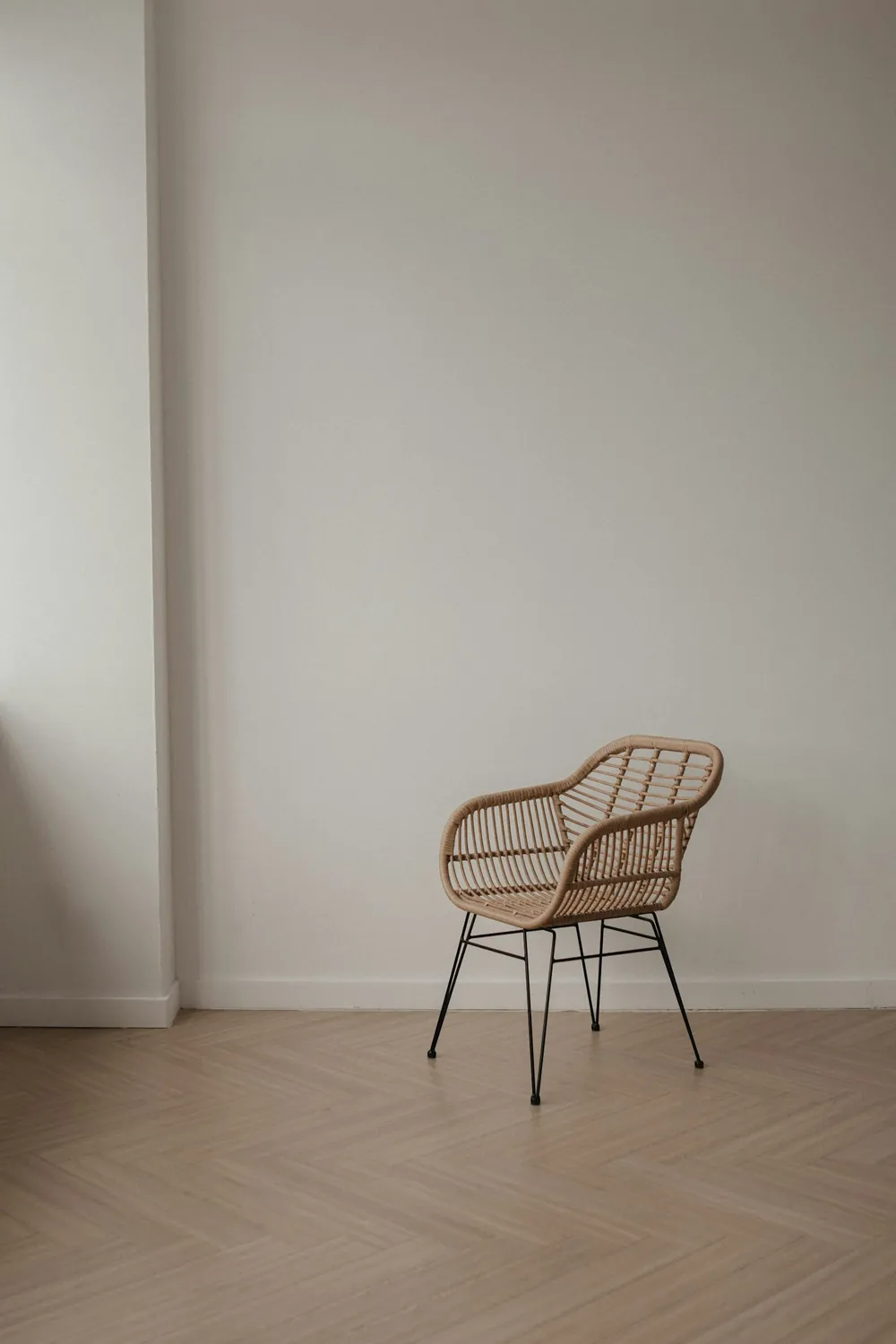 Silla de mimbre junto a un muro claro con luz natural